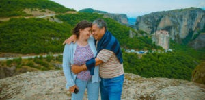 A middle-aged husband and wife embrace on an picturesque overlook in the hillsides of Greece