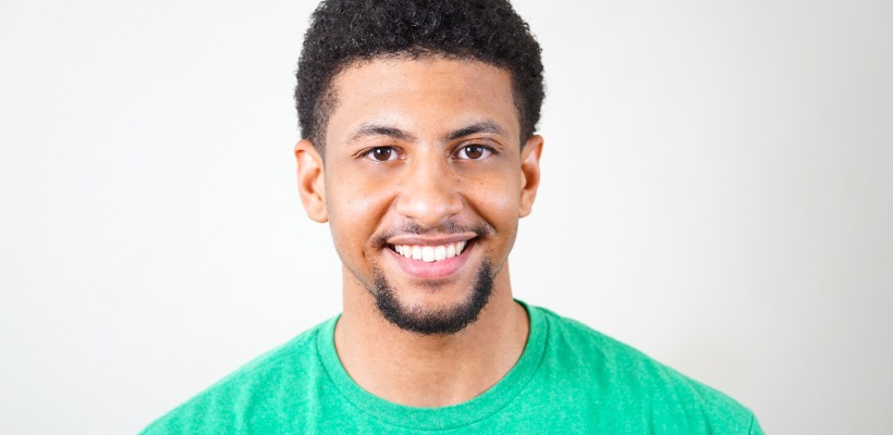 Brunette man with a chin beard and a green shirt smiles with teeth free of plaque