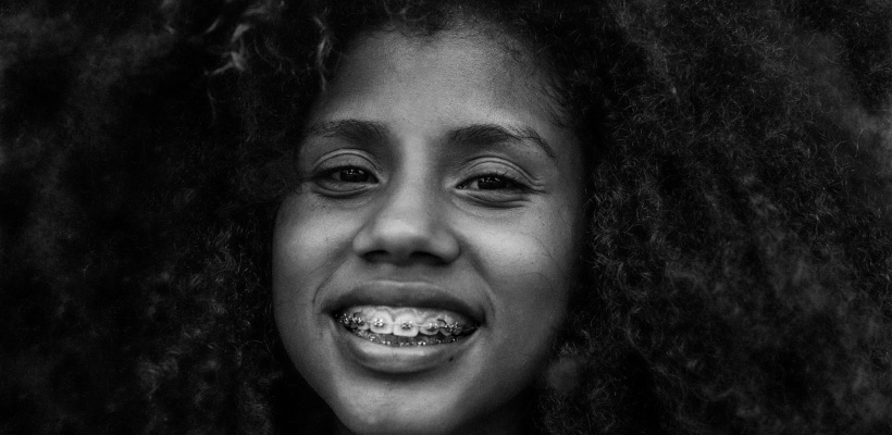 young girl with frizzy black hair and braces on her teeth