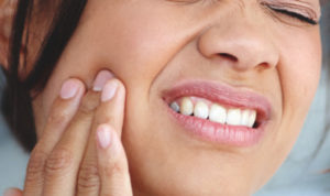 woman holding her cheek with tooth pain requiring a tooth extraction