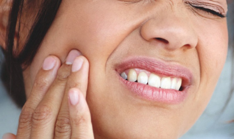 woman holding her cheek with tooth pain requiring a tooth extraction