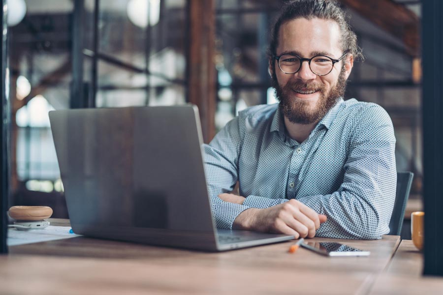 Young businessman with braces sitting in front of a laptop computer.