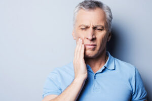 Mature man with his hand to his cheek due to tooth pain.