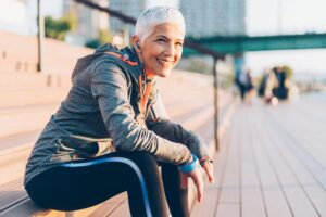 Smiling senior woman sitting on a bench after a workout.