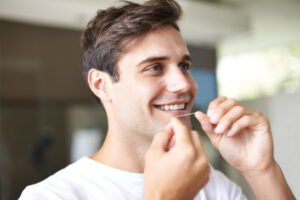 Man shown flossing his teeth.